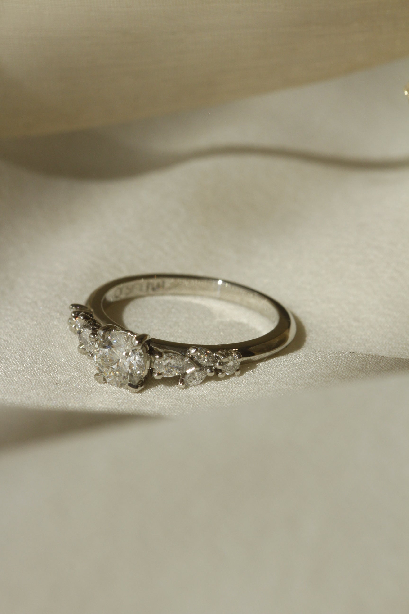 Nesso engagement ring design in 18k white gold lying on white fabric